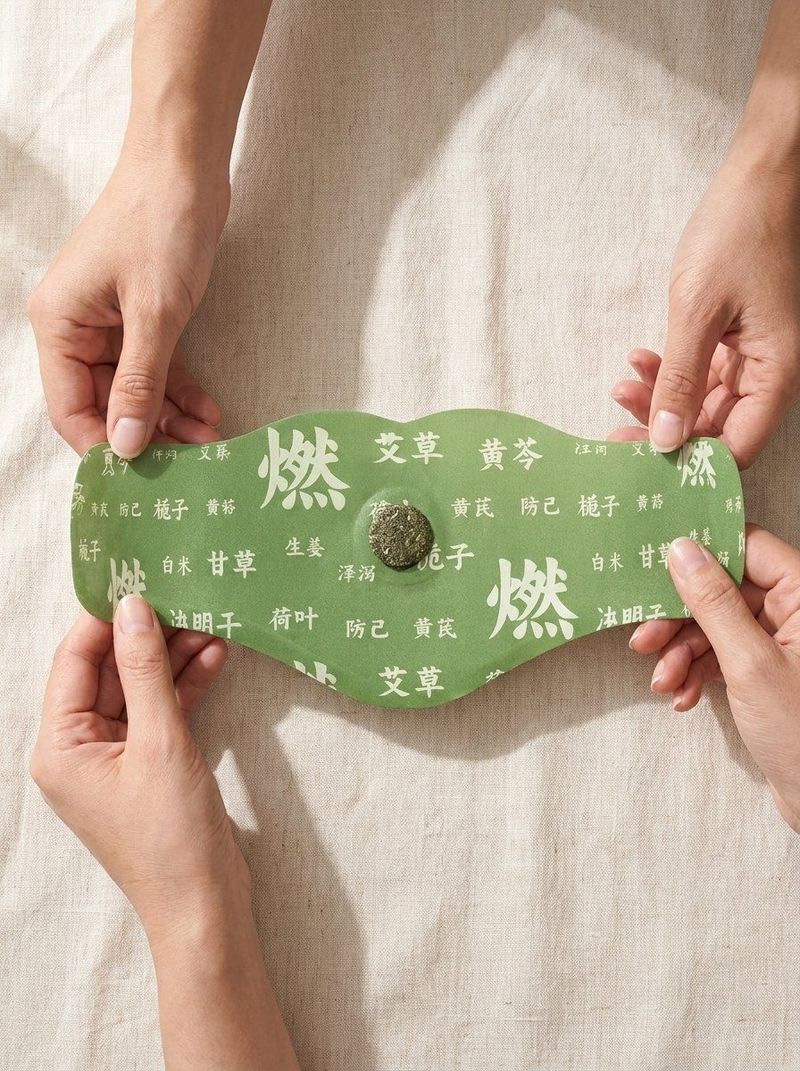 Two pairs of hands gently holding the Uvyna herbal balance patch at its edges, revealing the green herbal surface, traditional botanical characters, and the dark herbal core at its center, photographed on a soft linen background
